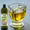 A bottle of olive oil and a glass pitcher filled with olive oil. Produktbild-Vorschau