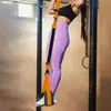 A woman is using a pull-up assist band attached to a pull-up bar in a gym. Anteprima dell’immagine prodotto