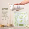 A hand pouring vegan protein powder from a shaker into a glass, with a bag of the product in the background. Anteprima dell’immagine prodotto
