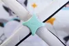 A close-up of a teal star-shaped clip holding together two padded straps of a baby playmat. Náhled obrázku produktu
