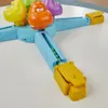 A close-up of a children's toy, a Hungry Hippos launcher, with green marbles loaded. Produktbild-Vorschau