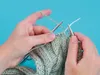 Hands knitting with light green yarn and silver knitting needles. Produktbild-Vorschau