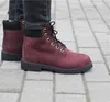 A person wearing burgundy Timberland boots and dark jeans standing on a paved walkway. Voir les images du produit