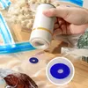 A hand is holding a white vacuum sealer device over a clear plastic bag with a blue valve, demonstrating its use for food preservation. Produktbild-Vorschau
