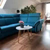 A living room scene with a blue sectional sofa and a white and wood coffee table set. Produktbild-Vorschau