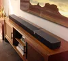 A soundbar is placed on a wooden media console in front of a television displaying a landscape image. Podgląd zdjęcia produktu