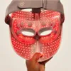 A hand holds up a red LED face mask with a gray strap. Anteprima dell’immagine prodotto
