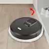 A black robot vacuum cleaner with a white mop pad is cleaning a wooden floor near a white wall and a pair of white shoes. Podgląd zdjęcia produktu