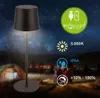 A portable LED table lamp is shown in a nighttime outdoor setting, possibly a campsite, with a tent and people in the background. The starry sky and distant lights add to the atmosphere. Náhľad obrázku produktu