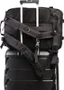 The back of a black backpack is attached to the handle of a black rolling suitcase. Náhled obrázku produktu
