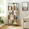 A modern living room with a bookshelf filled with decor and books, next to a sofa and a large window. Podgląd zdjęcia produktu