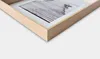 A close-up view of the corner of a wooden picture frame with a white mat and a black and white photograph inside. Anteprima dell’immagine prodotto