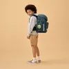 A young boy wearing a backpack stands against a plain background. Produktbild-Vorschau