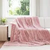 A pink fleece blanket draped over a white sofa in a well-lit room with a window overlooking greenery. Náhľad obrázku produktu