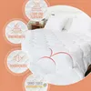 A white comforter is shown on a bed with pillows, with several circular overlays highlighting product features. Produktbild-Vorschau
