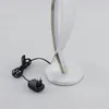 A close-up shot of a modern LED table lamp with a silver base and a curved, white light element. A black power cord and adapter are visible on the left. Produktbild-Vorschau