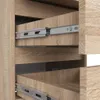Close-up view of two open drawers with metal drawer slides, showing the wood grain texture of the drawer fronts and the interior of the cabinet. Podgląd zdjęcia produktu