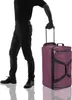 A person stands next to a large purple duffel bag with wheels. Produktbild-Vorschau