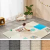 A baby is playing on a colorful play mat in a room with a teddy bear chair and a plant. Náhľad obrázku produktu