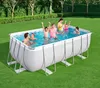 A family is enjoying themselves in a rectangular above-ground swimming pool set up on a green lawn. Produktbild-Vorschau