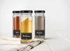 Three spice jars labeled 'Chili', 'Kurkuma', and 'Pepper' are arranged on a white wooden surface with a striped cloth underneath. Produktbild-Vorschau