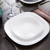 A table setting with white square plates and a wine glass. Anteprima dell’immagine prodotto