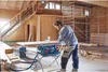 A man is using a Bosch table saw in a workshop with scaffolding in the background. Voir les images du produit