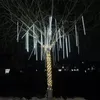 A tree decorated with white meteor shower lights and yellow string lights at night. Náhled obrázku produktu