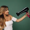 A woman is drying her hair with a hairdryer. Produktbild-Vorschau