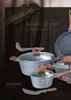 A collection of granite cookware with wooden handles and glass lids, set against a dark, textured background with a rustic wooden sign and moss. Náhľad obrázku produktu