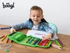 A young boy is sitting at a wooden table, drawing with colored pencils from an open pencil case. Podgląd zdjęcia produktu