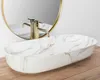 A close-up shot of a marble-patterned vessel sink with a gold faucet, set against a white background and a wooden surface. Náhľad obrázku produktu