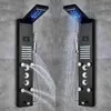 Two black shower panels with LED lights and multiple shower heads are mounted on a gray tiled wall. Náhľad obrázku produktu