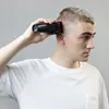 A person is using a hair clipper on their own head. Podgląd zdjęcia produktu