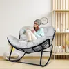 A woman sits in a rocking chair while using a tablet. Produktbild-Vorschau