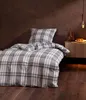 A bed with plaid bedding in a room with a dark brown wall and wooden floor. Produktbild-Vorschau