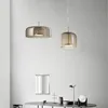 Two modern pendant lights hang above a table with decorative items and a mirror on the wall. Náhled obrázku produktu