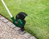 A grass trimmer is being used to trim the edge of a lawn next to a stone pathway. Produktbild-Vorschau