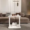 A white C-shaped side table with books and cups on it, placed in front of a brown sectional sofa in a living room. Anteprima dell’immagine prodotto