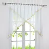 A white sheer curtain with gold trim hangs on a window. Produktbild-Vorschau