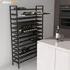 A black metal wine rack filled with wine bottles, placed in a modern kitchen setting next to a white countertop and oven. Anteprima dell’immagine prodotto