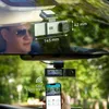 A split image showing a dashcam mounted on a car windshield in the top half, and a person holding a smartphone displaying the dashcam's feed in the bottom half. Produktbild-Vorschau