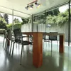 A modern dining room with large windows overlooking a garden, featuring a wooden dining table and chairs. Anteprima dell’immagine prodotto