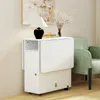 A white folding table with storage is shown in a room with a green chair and a painting on the wall. Produktbild-Vorschau