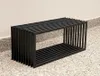 A black metal bench is placed on a gravel and concrete surface next to a light-colored wall. Anteprima dell’immagine prodotto