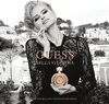 A woman is holding a perfume bottle in front of a cityscape. Voir les images du produit