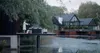Two people relaxing in a hot tub on a deck next to a modern house by a lake. Náhled obrázku produktu