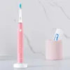 A pink electric toothbrush and a tube of toothpaste in a pink holder are displayed on a counter with a marble-patterned wall in the background. Podgląd zdjęcia produktu