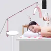 A woman is lying on a massage table with a lamp positioned above her. Náhľad obrázku produktu