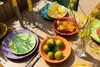 A table setting with colorful plates, food, and flowers. Produktbild-Vorschau